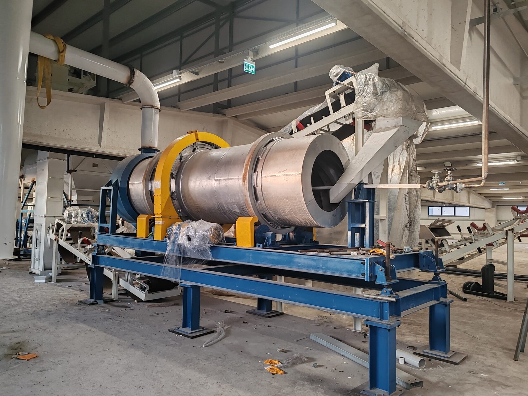 Rotary drum granulator with riding rings, trunnion rollers, and gear drive.